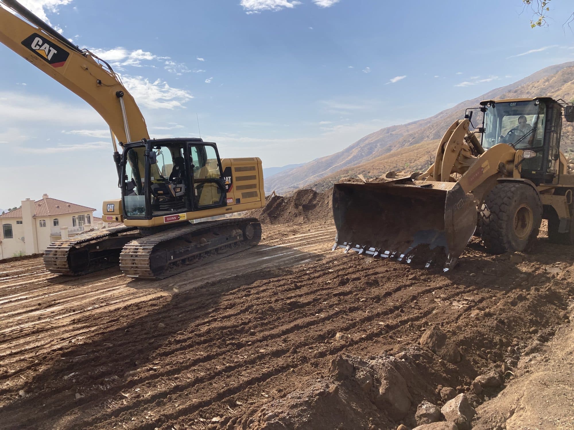 CAT excavator and wheel loader grading a large dirt site
